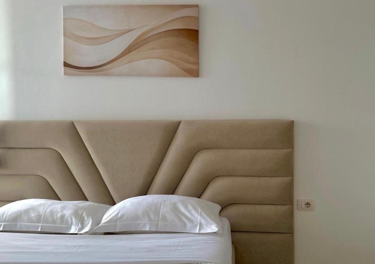 Upholstered headboard detail with crisp white linen